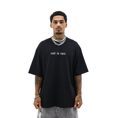 Black "Real is Rare" T-shirt by HeightsDistrict displayed flat on a white background, showcasing the front design.